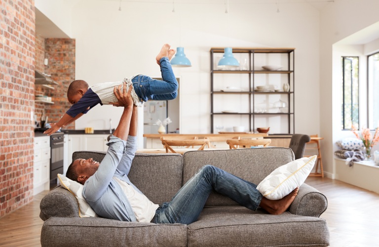 Father And Son Having Fun Playing On Sofa Together