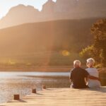 Old couple sitting on the end of a dock_s