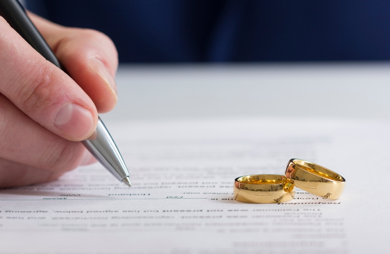 Person writing on paper with wedding bands