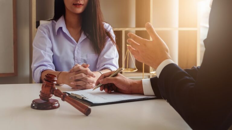 Two individuals in a legal consultation, with a gavel and scales of justice on the table.