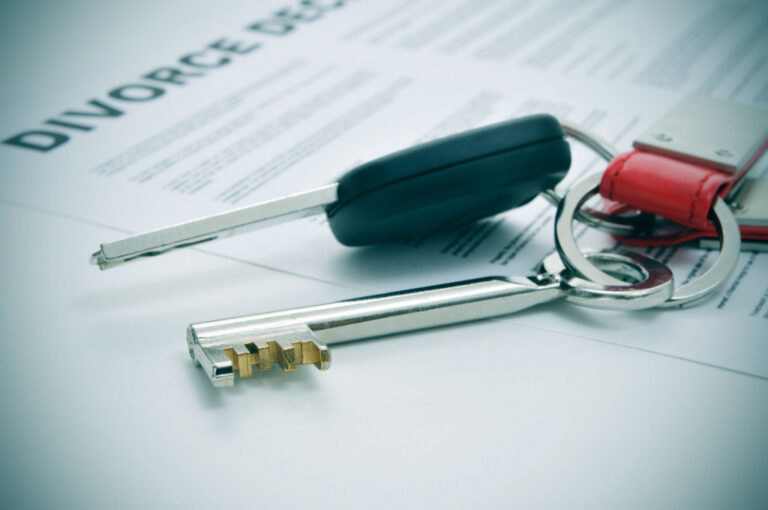 Close-up of a set of keys placed on a divorce decree document with visible text.