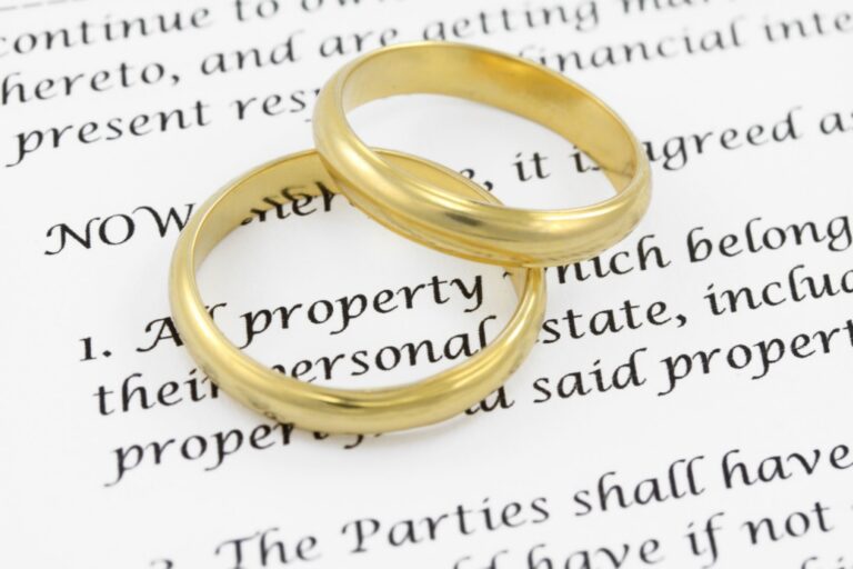 Two gold wedding bands resting on a legal document with black printed text.