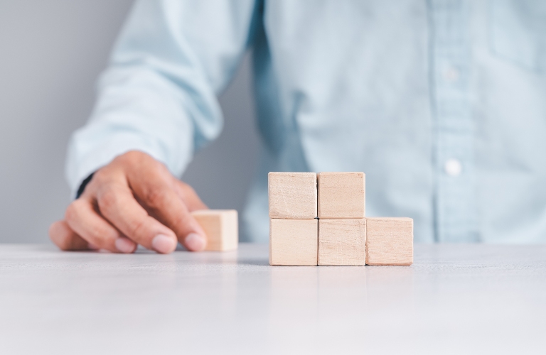 Businessman wearing a blue shirt, arranging the empty wooden blocks with his hands