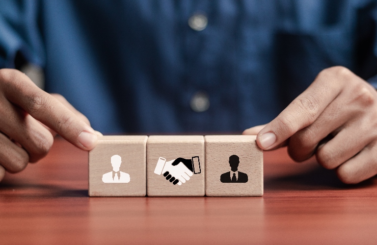 Wooden block with handshake icon and businessman icon