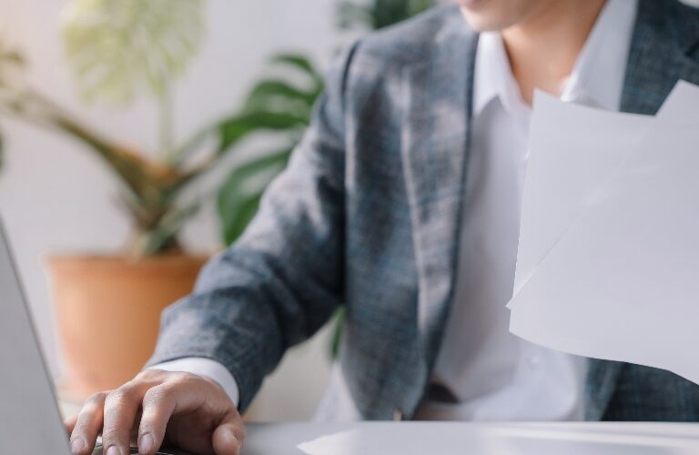 Man holding papers and a computer