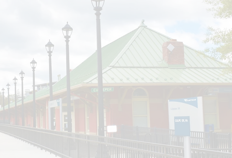 Exterior view of Culpeper, VA Amtrak station with green roof and red brick walls.